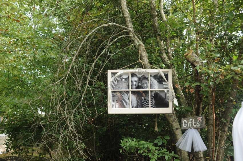 Family photographs displayed in a vintage window frame hanging in the woods